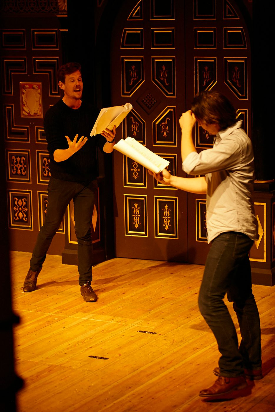 Two actors perform on stage with scripts