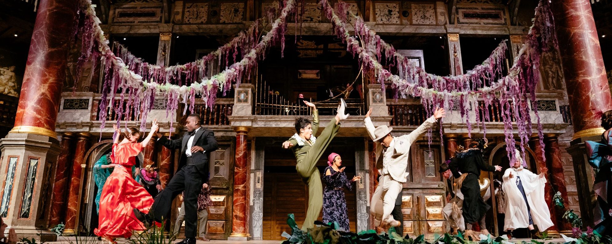 A group of actors dressed in party clothes dancing on stage