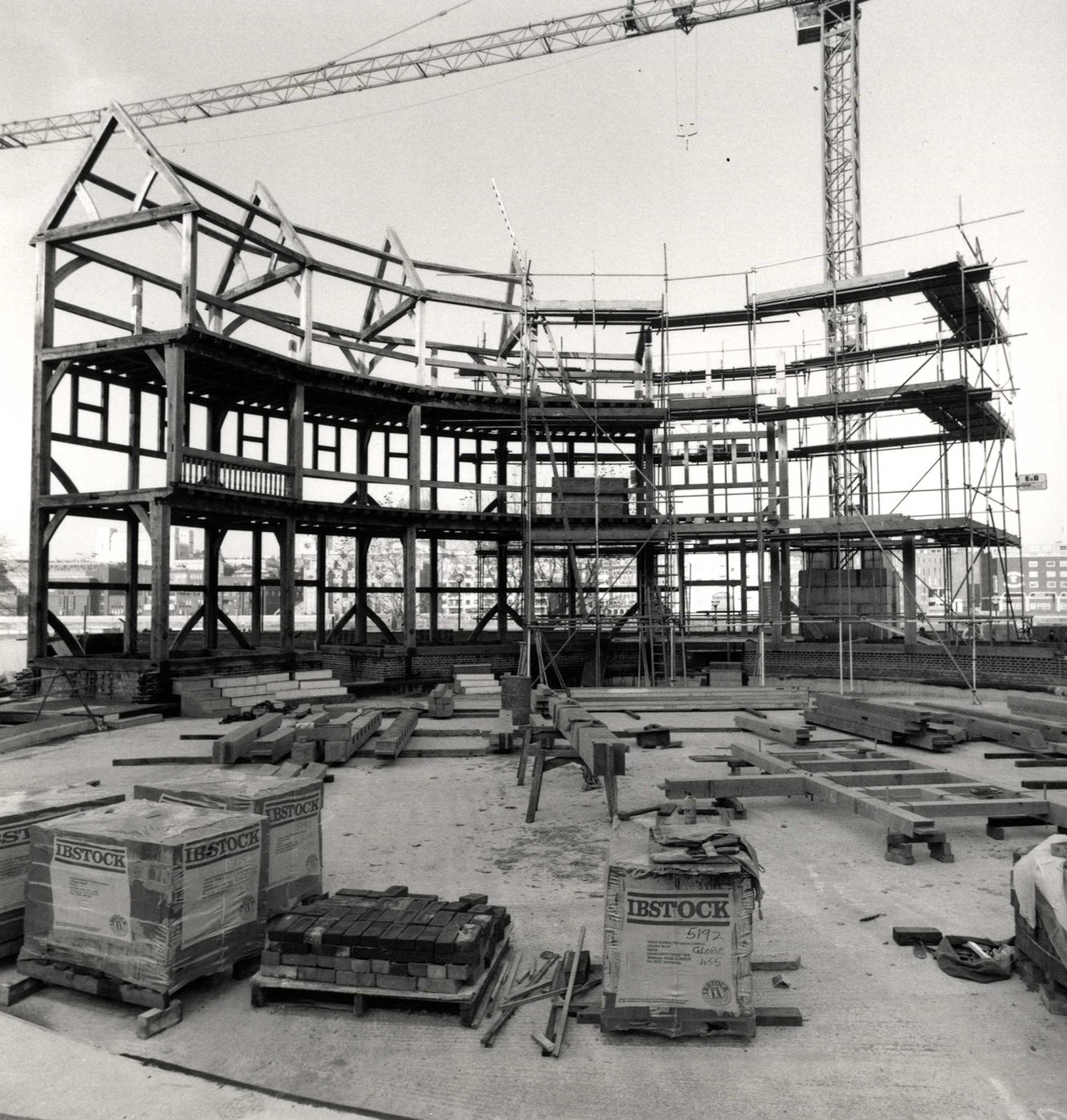 A timber circular structure starts to take shape on a construction site, with a crane in the background.