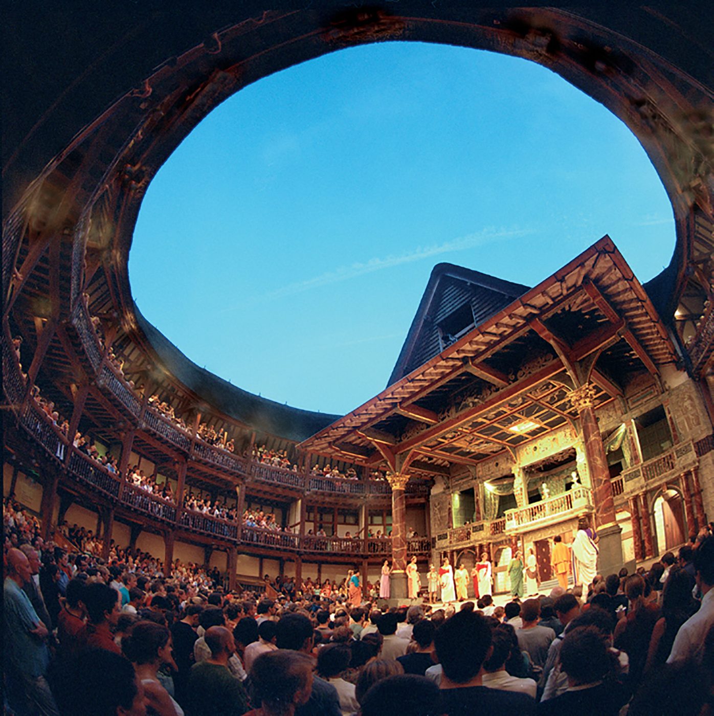 A circular inside photograph of a timber structure theatre, filled with audiences.