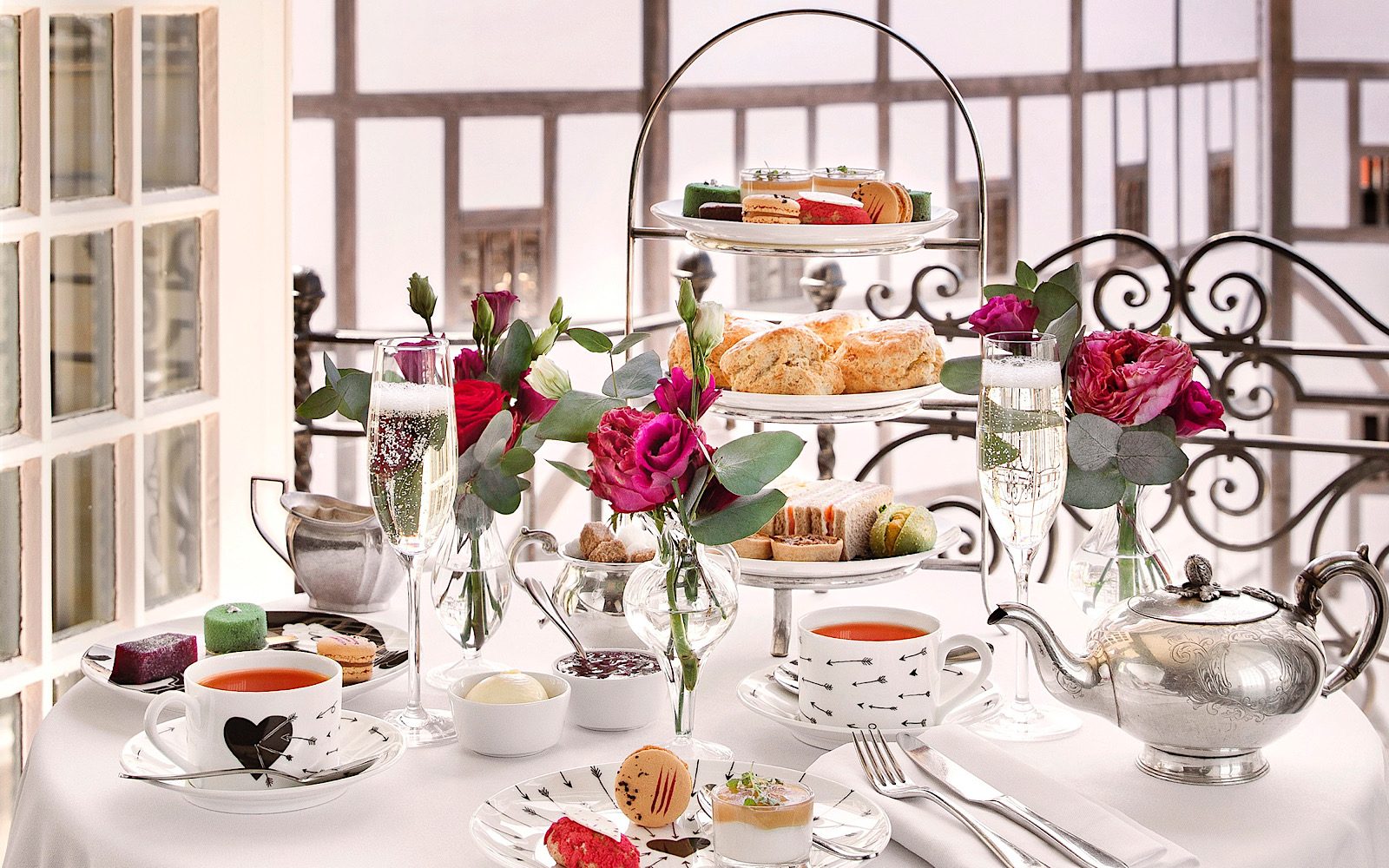 A lavish table set-up of afternoon tea shows tea, cakes and intricate crockery