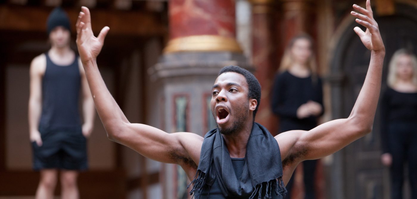 A student raises his hands in the air acting in a performance