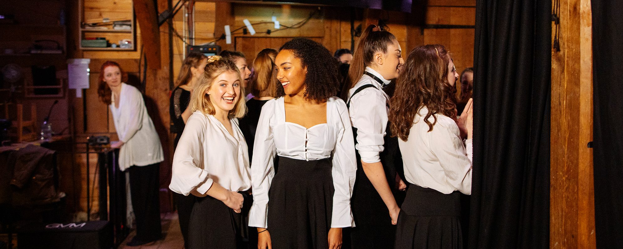 A group of performers are backstage at a theatre ready to go on stage