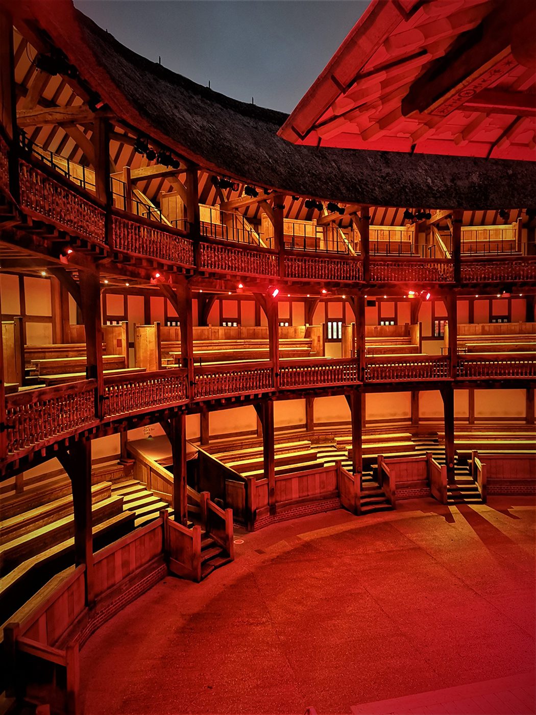 The inside galleries of the Globe Theatre are bathed in a red light.