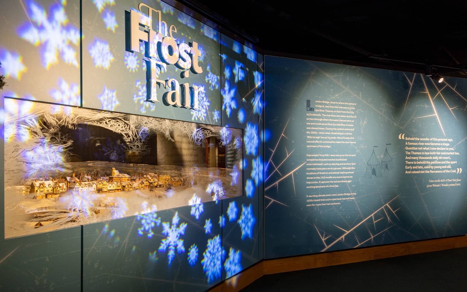 A blue backgrounded display with snow flake images shining onto the display with text that reads 