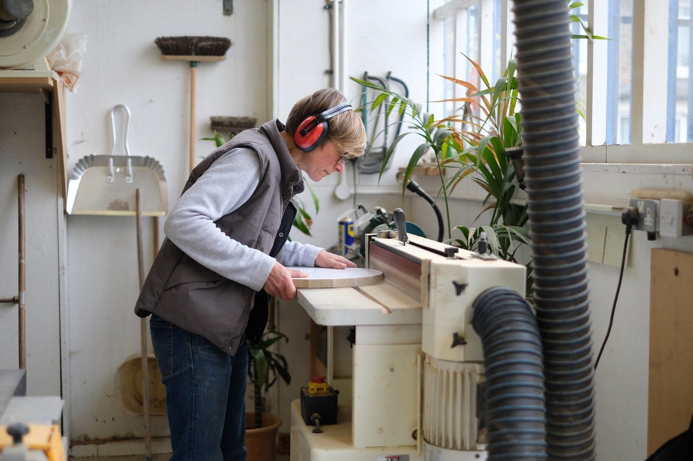 An artist works with a machine to carve a piece of wood