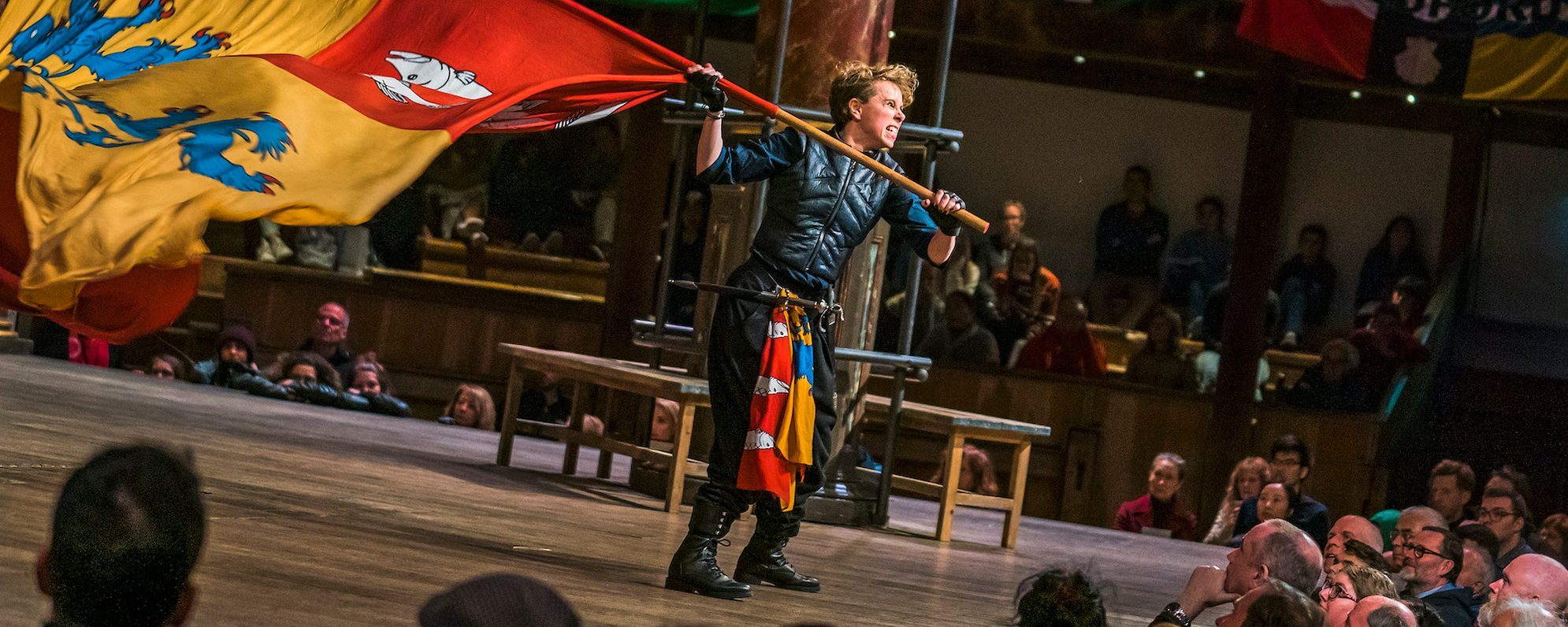 An actor on stage holding a large red and yellow flag