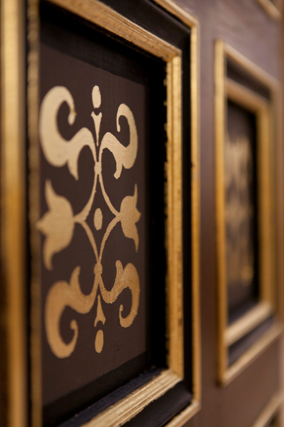 Detail on a black wall shows gold patterns