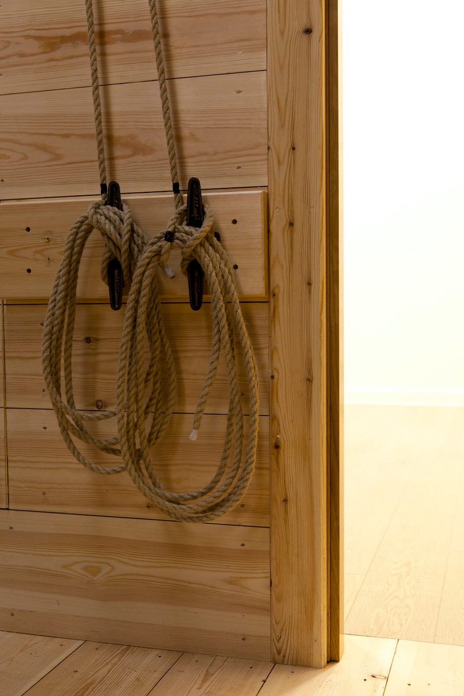 Ropes are tied to handles against a wooden wall