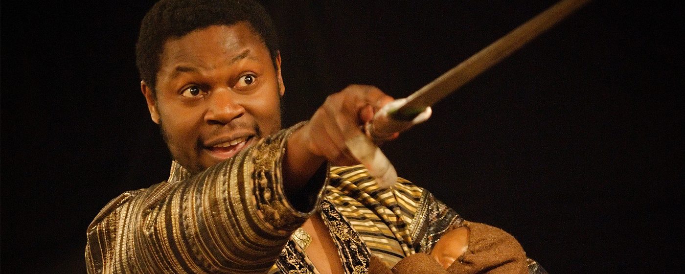 An actor points with a sword