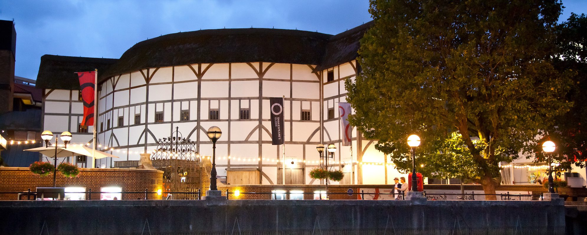 A thatched theatre at night illuminated by string lights