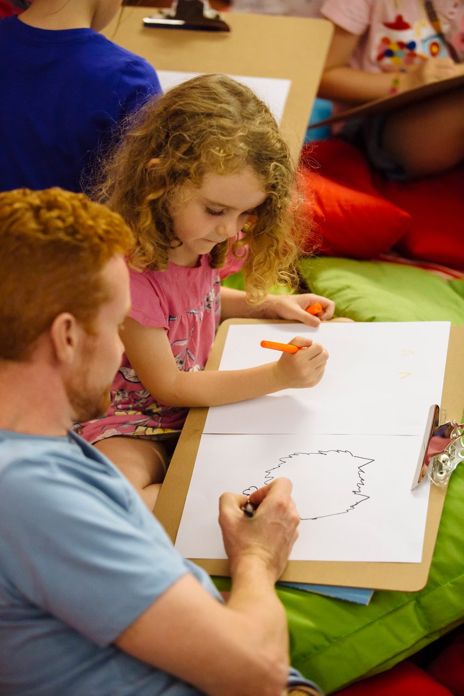 An adult and a child draw on pieces of paper together