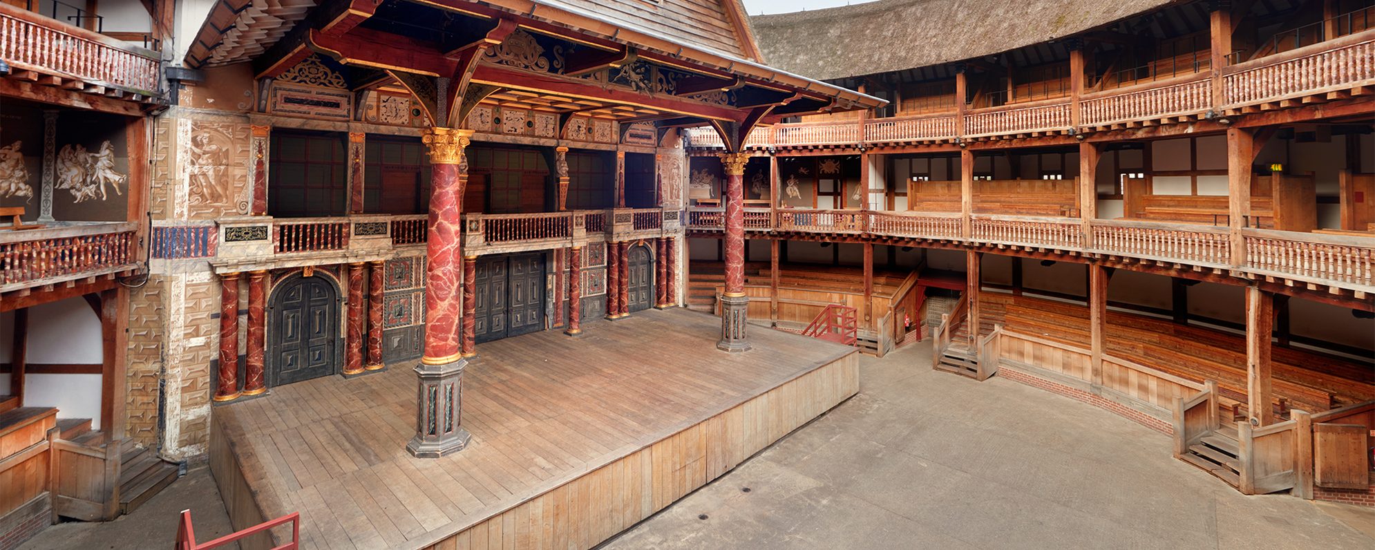 A view of an empty Globe Theatre, the image pans across the stage and seating bays.