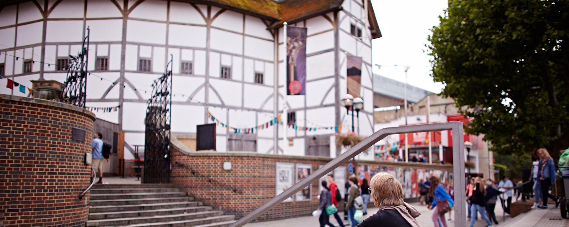 A woman sits outside a white theatre