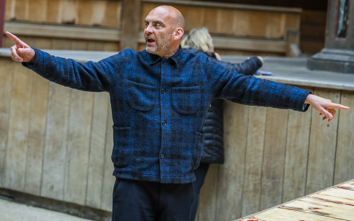 The director of a play uses his fingers to point as he is directing his actors in rehearsals