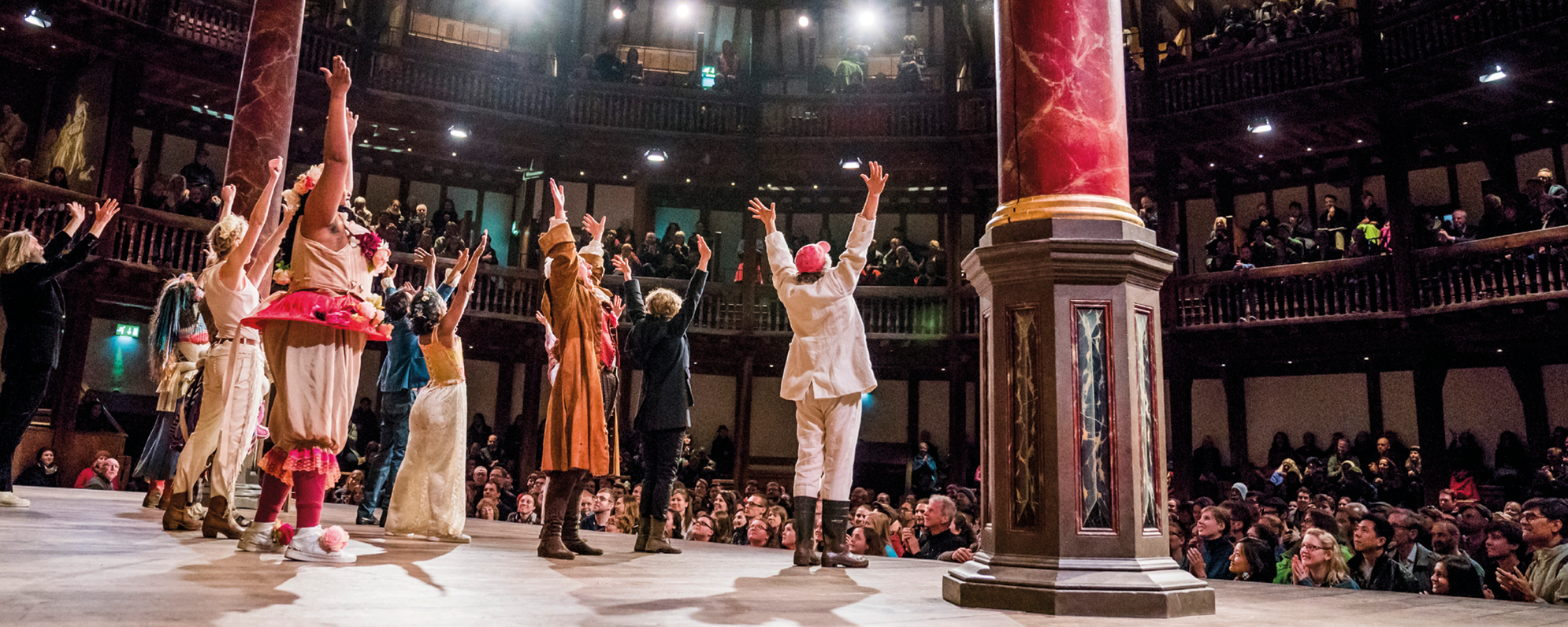 [IMAGE] A group of actors stand on the Globe stage ready to take a bow