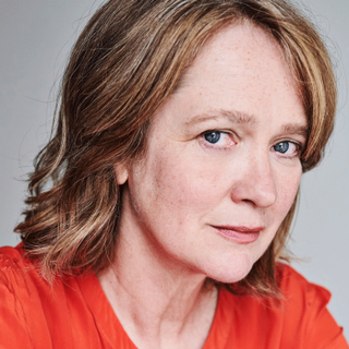 Headshot of Poppy Miller in a red top looking straight to camera.